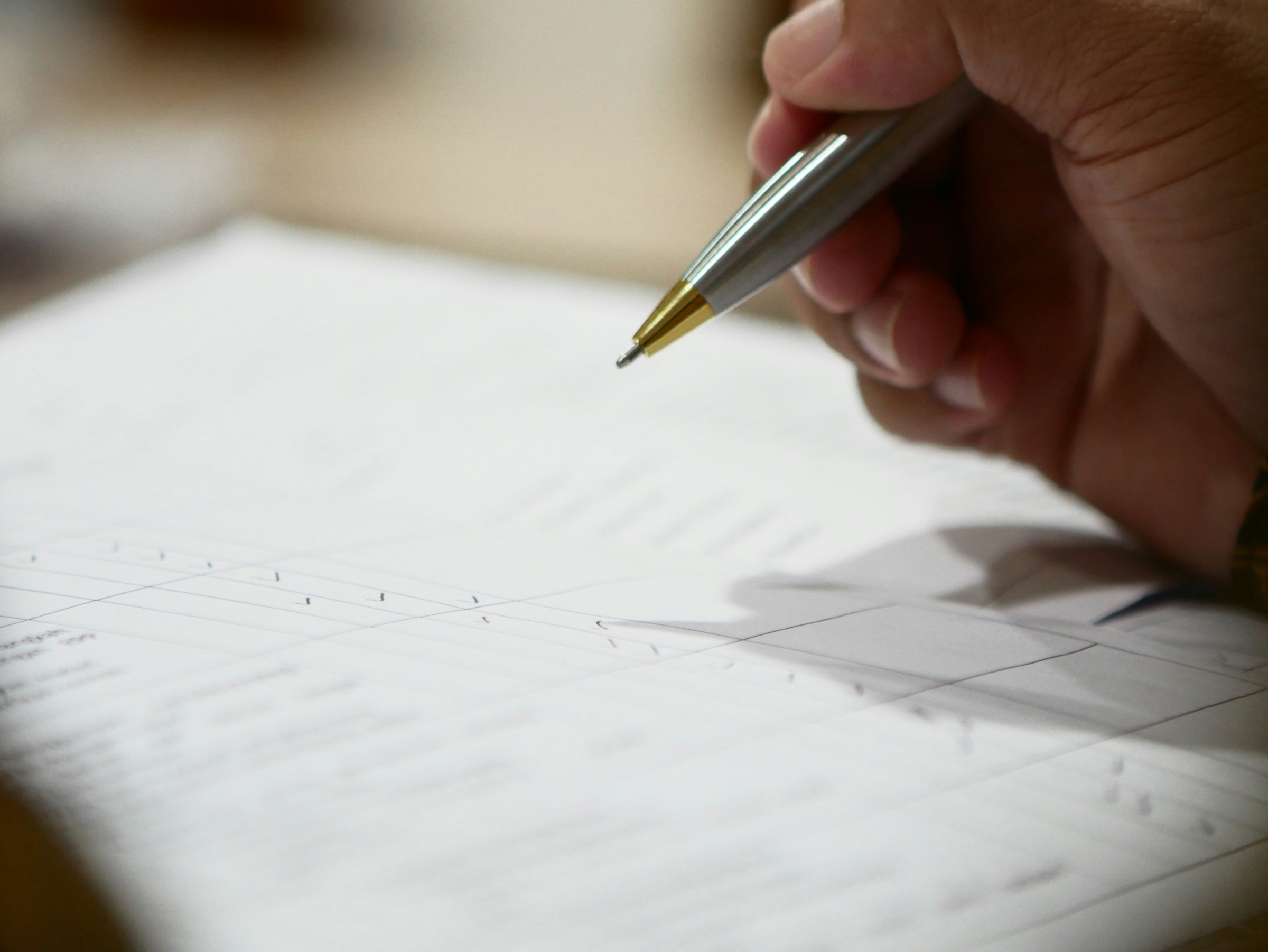 A hand going over financial records with a pen